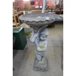 A concrete figural cherub bird bath