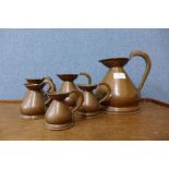A set of six small graduated copper jugs