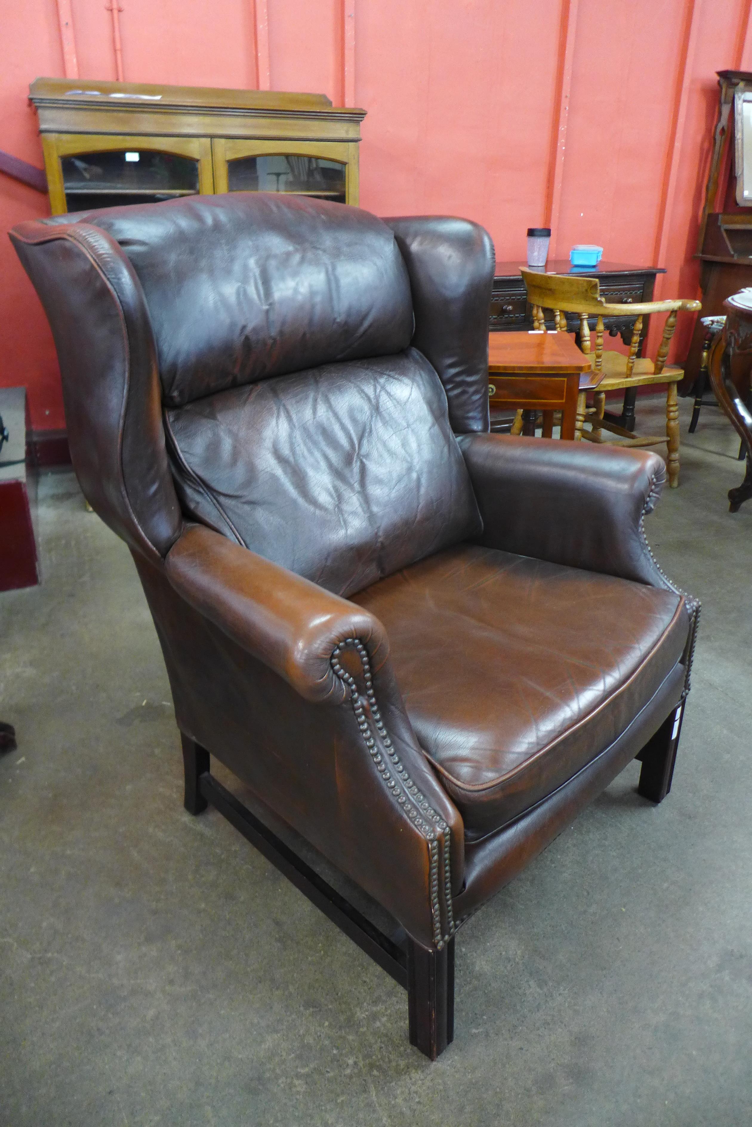 A mahogany and studded chestnut brown leather wingback armchair