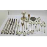 A collection of silver spoons, a candlestick, silver handled knives, a silver top, etc., weighable