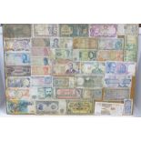 A collection of mounted banknotes, mainly foreign, a Peppiatt £1 note and an O'Brien ten shillings