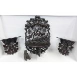 A Black Forest carved seated bear and three carved shelves