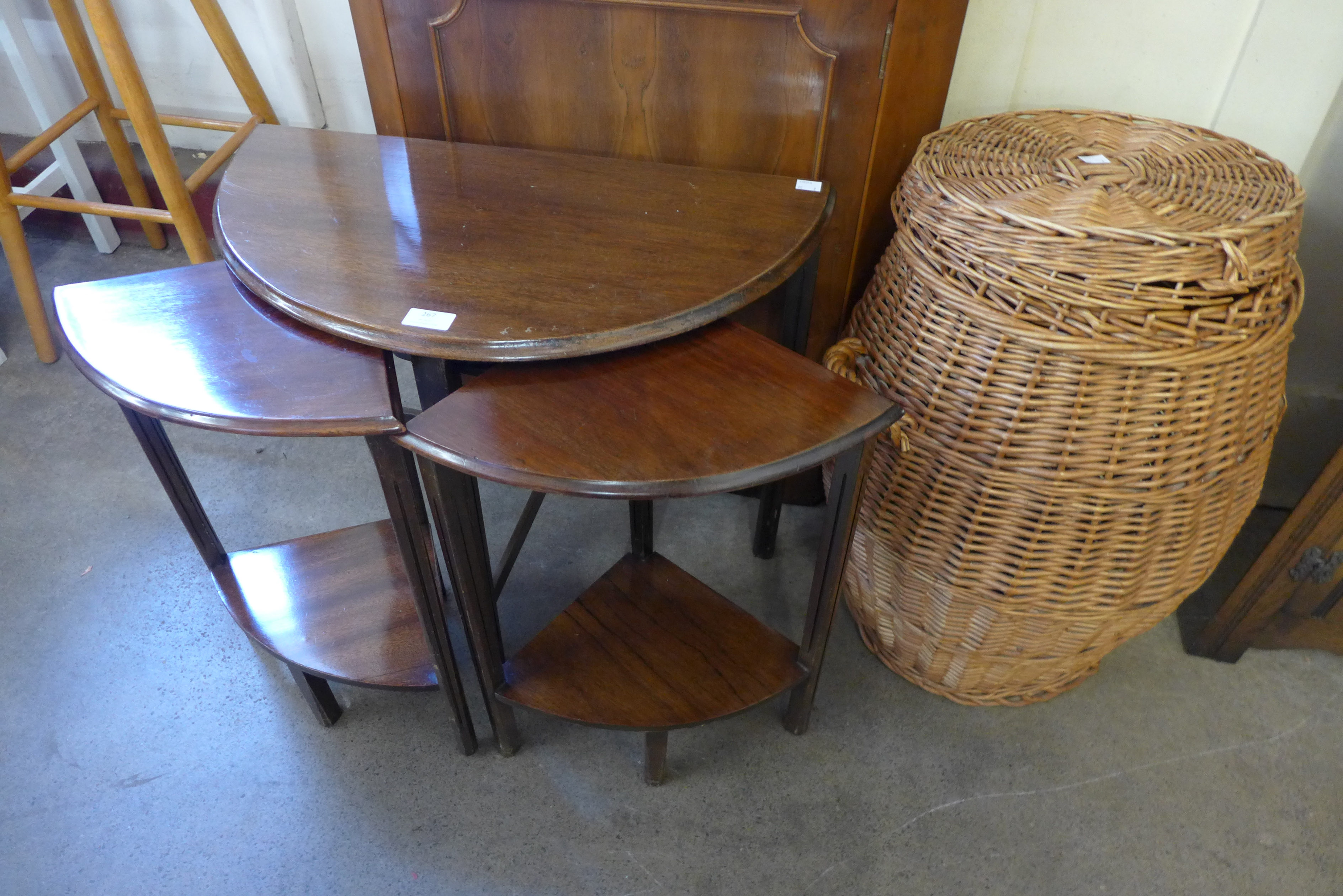 A wicker linen basket and a mahogany nest of tables