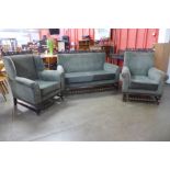 An early 20th Century carved oak and green fabric upholstered three piece lounge suite, attributed