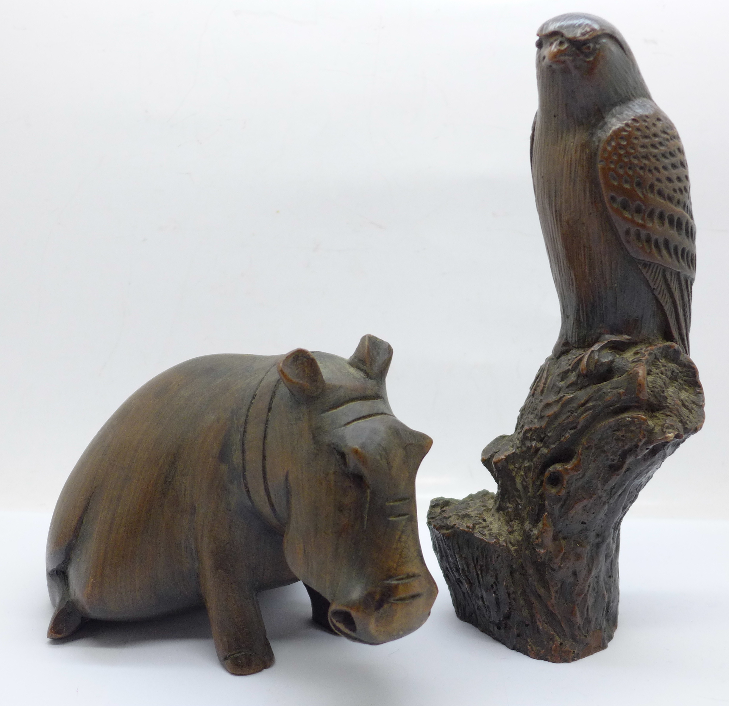 A carved wooden hippopotamus and a resin hawk