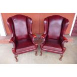 A pair of George III style mahogany and faux red leather highback wingback armchairs