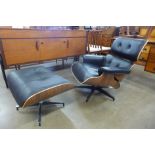 A Charles & Ray Eames style black leather, walnut effect and chrome revolving lounge chair and