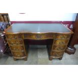 A mahogany and green leather topped serpentine desk
