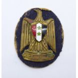 A Syrian army cap badge, (National Arms of Syria)