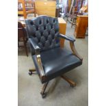 A mahogany and black leather revolving desk chair