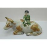 A china figure of a boy sitting on a cow