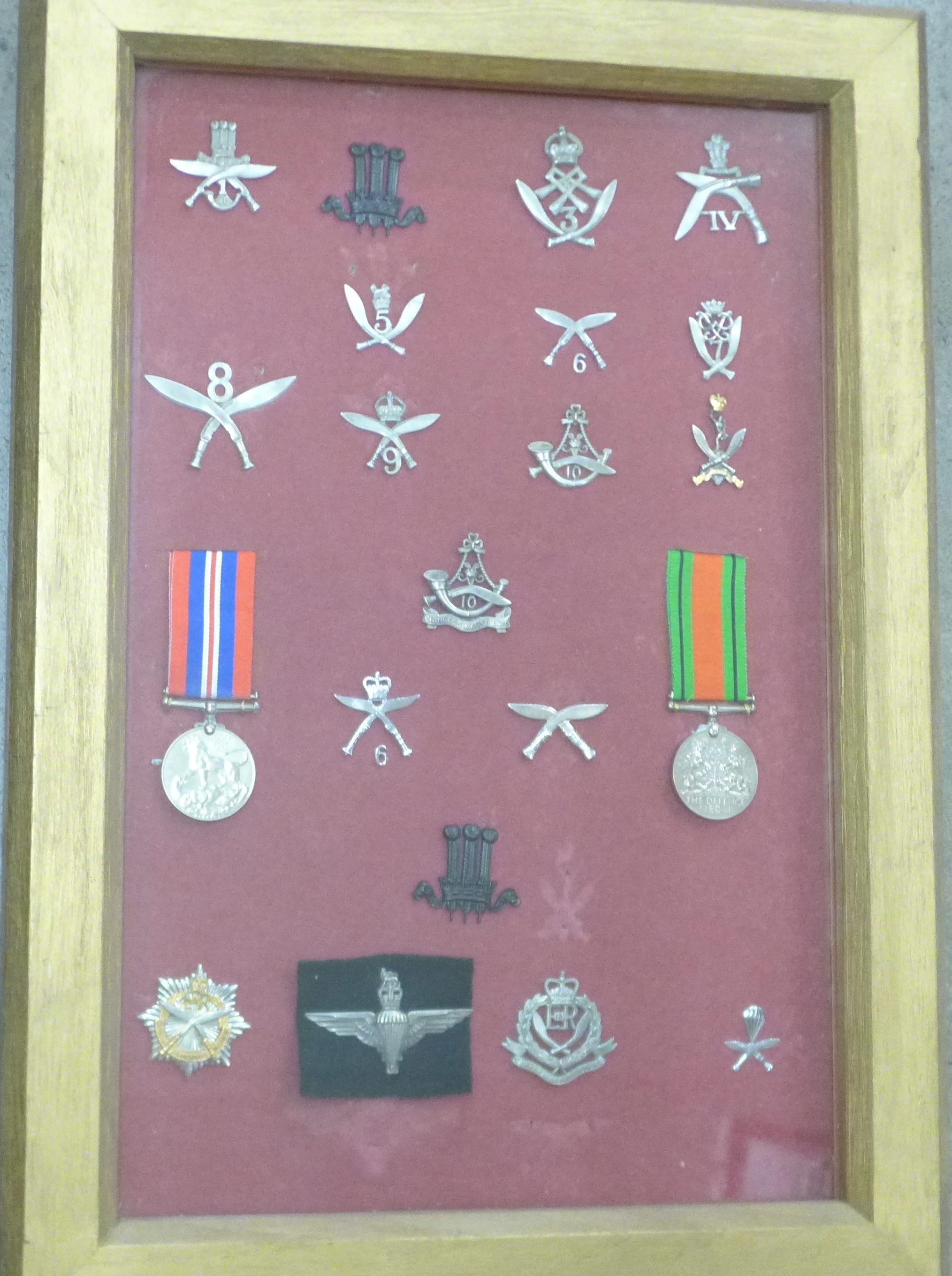 A collection of Ghurka badges and two WWII medals in a display case