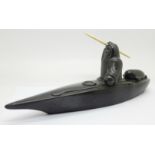 A carved soapstone model of an Inuit in a canoe, 26.5cm