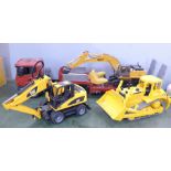 A Bruder transporter, two Caterpillar construction vehicles and a remote control digger, remote