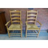 A pair of Arts and Crafts Cotswold School oak rush seated ladderback elbow chairs, attributed to