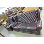 A red leather Chesterfield wingback settee and matching armchair