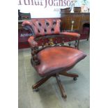 A mahogany and oxblood leather revolving captain's desk chair