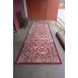 A red ground geometric patterned rug, 516 x 172cms