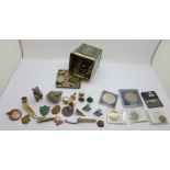 A tin of British and foreign coins and a collection of enamel badges, cufflinks, reproduction coins,