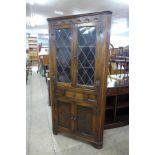 A carved oak four door freestanding corner cabinet