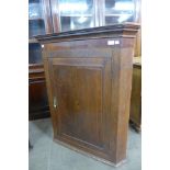 A George III oak splay front hanging corner cupboard