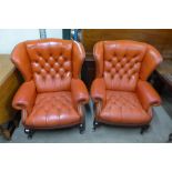 A pair of buttoned red leather wingback armchairs, one a/f