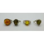 Four silver and amber rings, (two green amber)