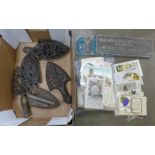 Three cast metal plaques, an iron and six trivets and a collection of postcards **PLEASE NOTE THIS