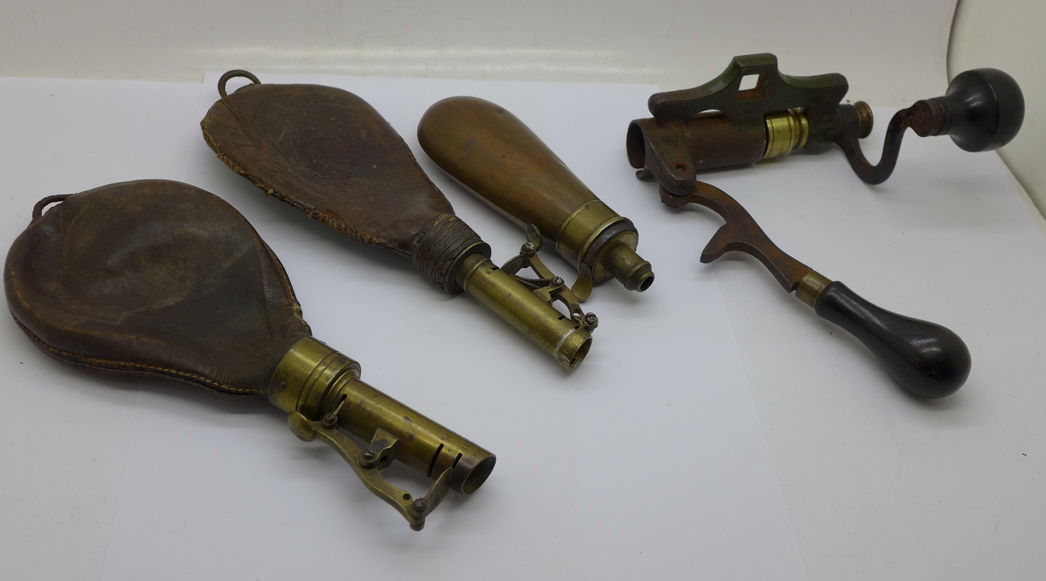 Two leather and brass shot flasks, a copper shot flask and a cartridge tool, James Dixon & Sons 12