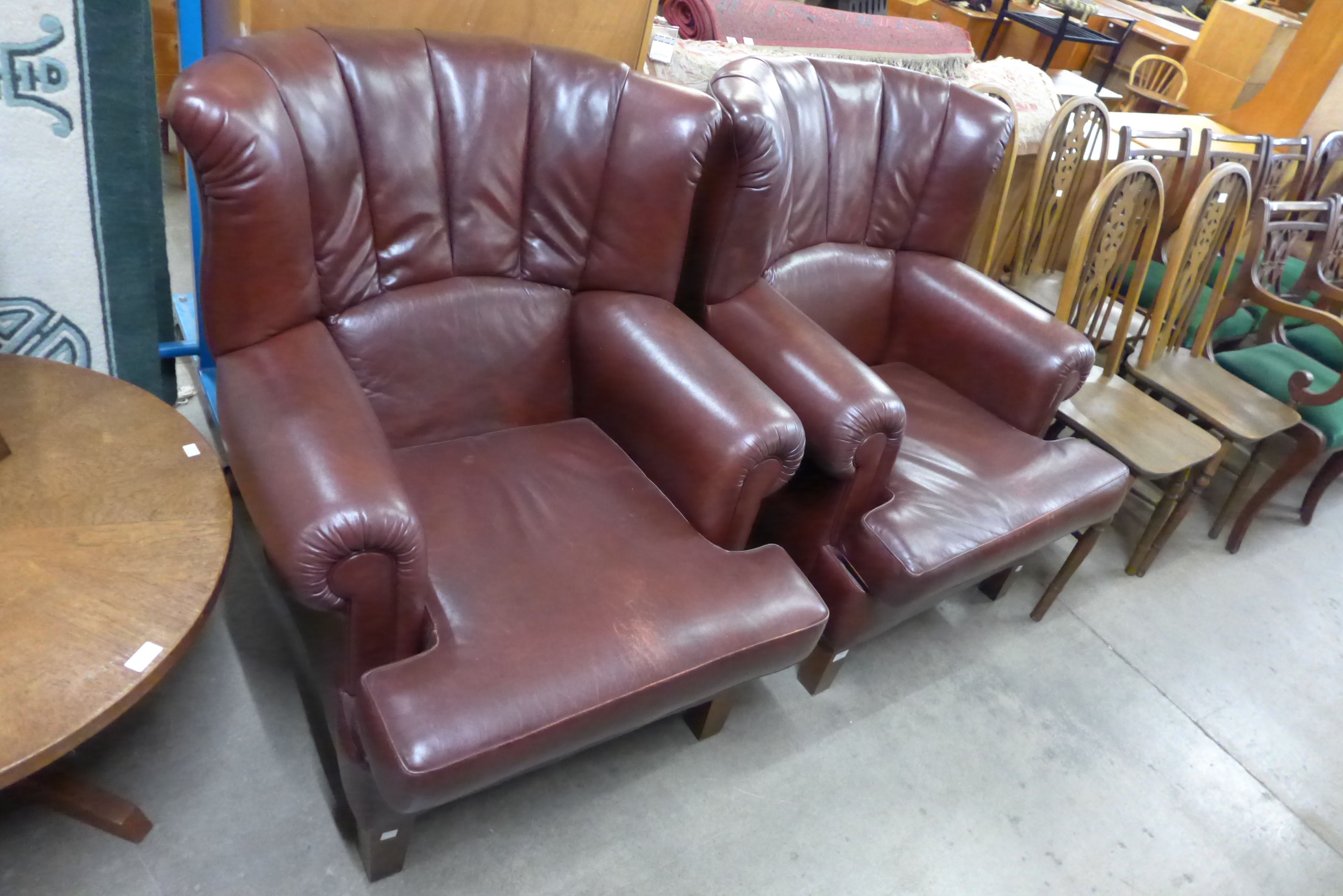 A pair of burgundy leather wingback armchairs