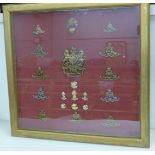 A display case with artillery regimental cap badges and buttons, including a helmet plate