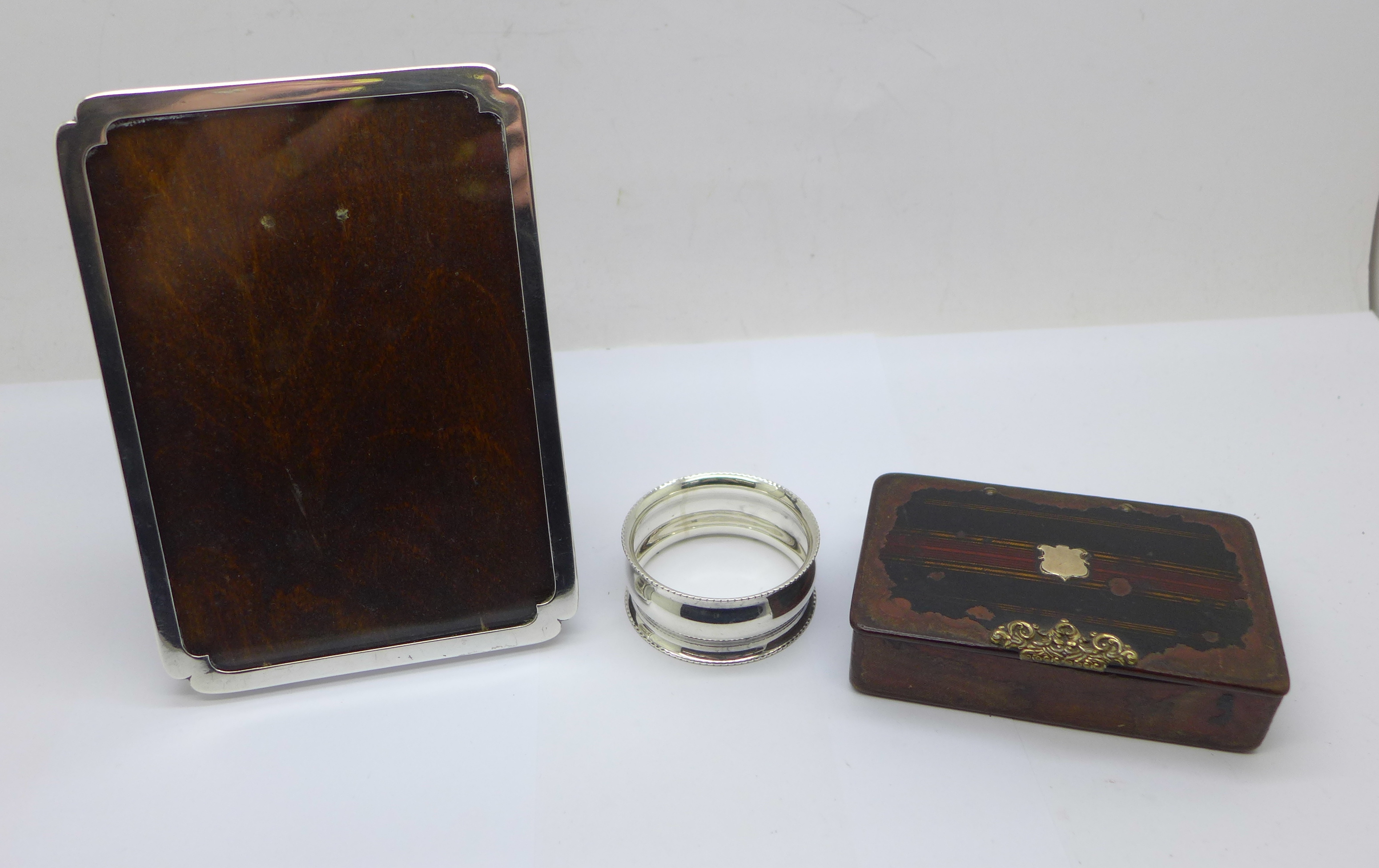 A silver photograph frame, a silver napkin ring and a Georgian snuff box, frame 9.5cm x 13cm, (snuff