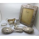 A silver photograph frame, a/f, a silver sauceboat, a/f, 110g, two silver backed brushes, a silver