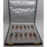 A cased set of twelve pewter and rose quartz place settings decorated with fruit