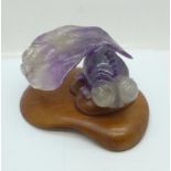 A carved amethyst quartz shubunkin on a wooden stand