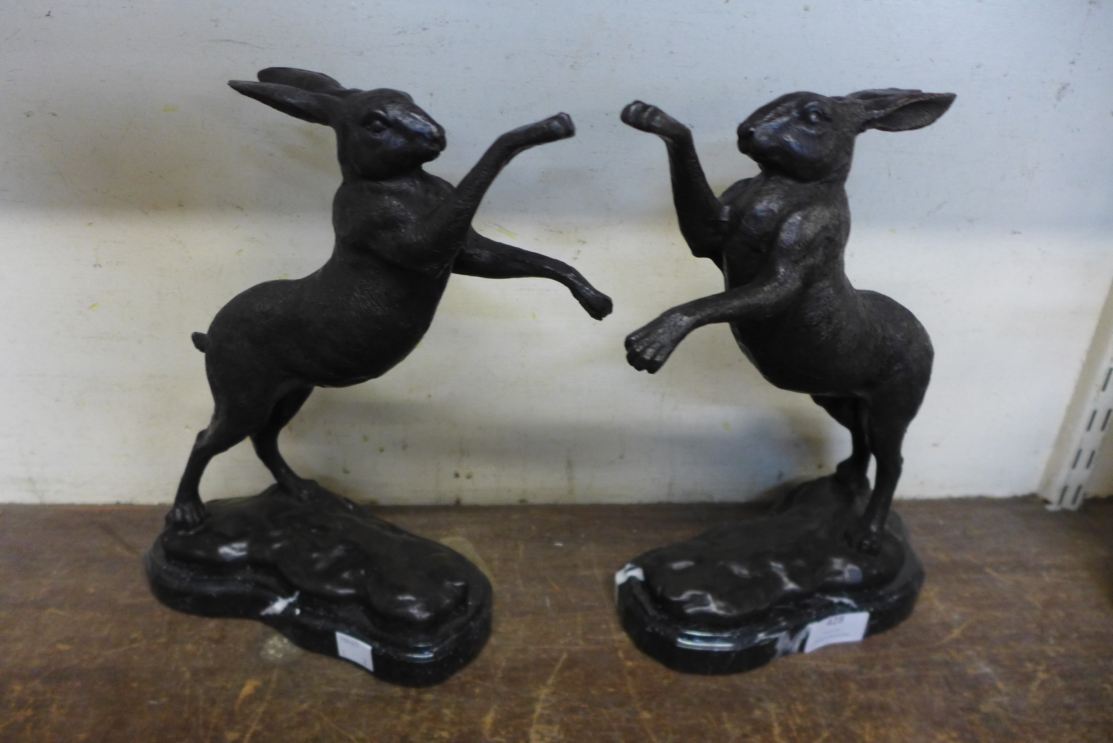 A pair of bronze boxing hares, on black marble plinths, 30cms h