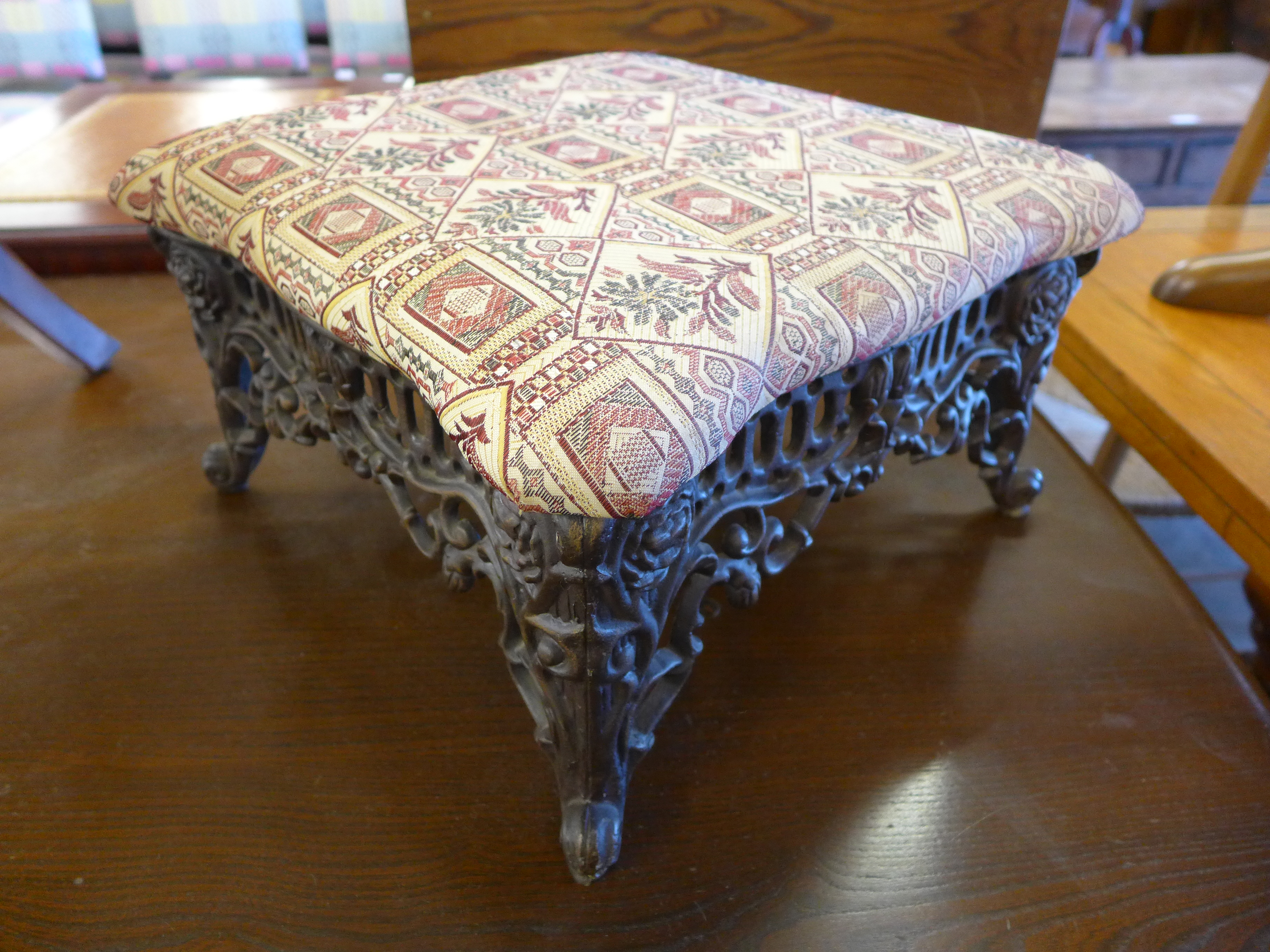 An Art Nouveau style cast iron and upholstered footstool