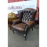 A chestnut mahogany and brown buttoned leather wingback armchair