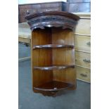 An Edward VII carved mahogany bow front wall hanging corner cabinet