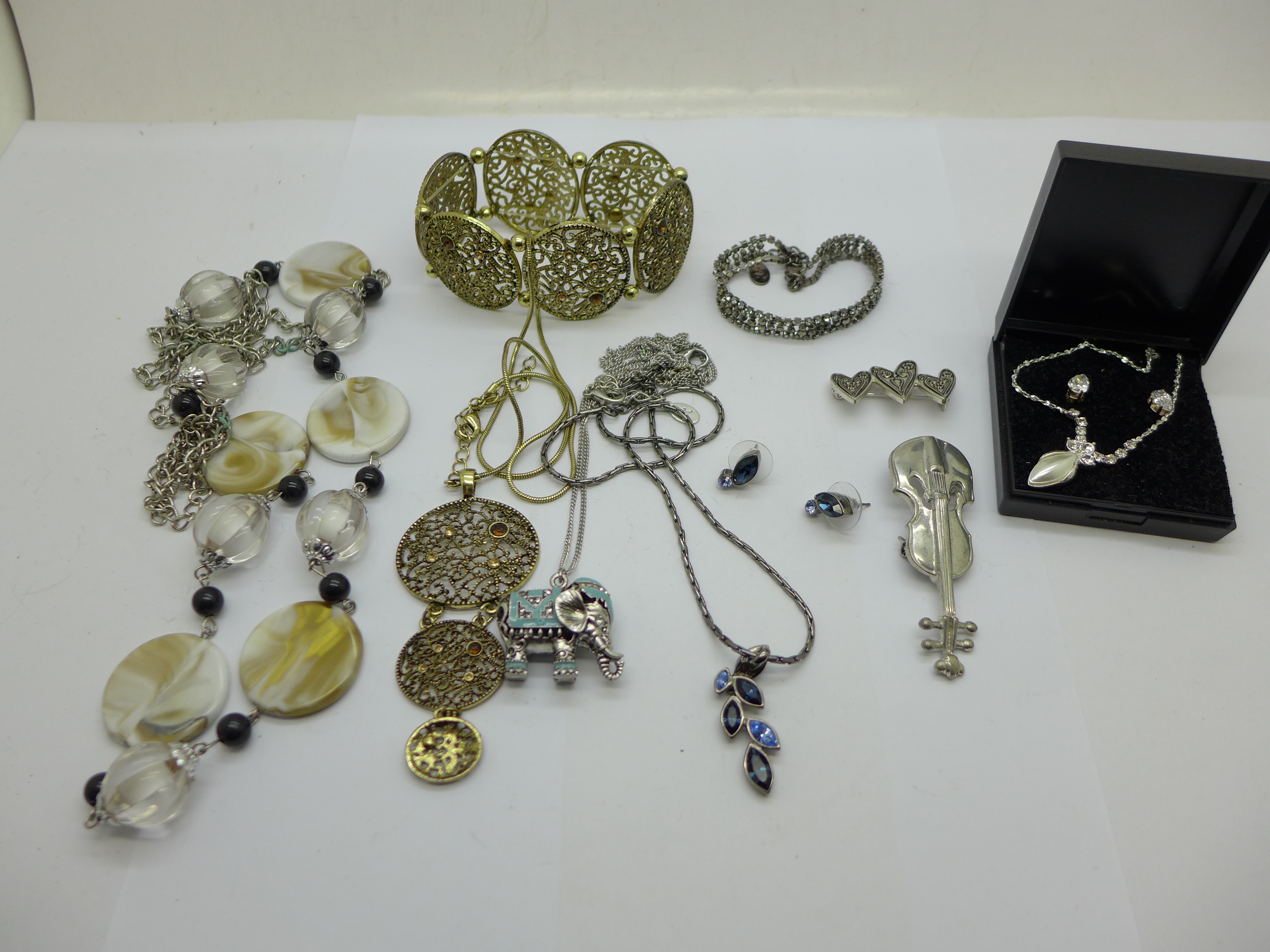 An elephant pendant on chain, two pairs of earrings and other necklaces and two brooches