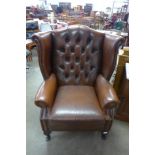 A mahogany and chestnut brown leather wingback armchair