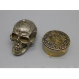 A metal skull trinket and a pill box set with a 1780 German one Thaler coin