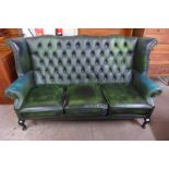 A green leather Chesterfield wingback settee ( tear to seat cushion)