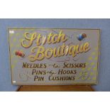 A painted wooden Stitch Boutique sign