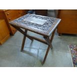 An Arts and Crafts carved oak X-frame occasional table