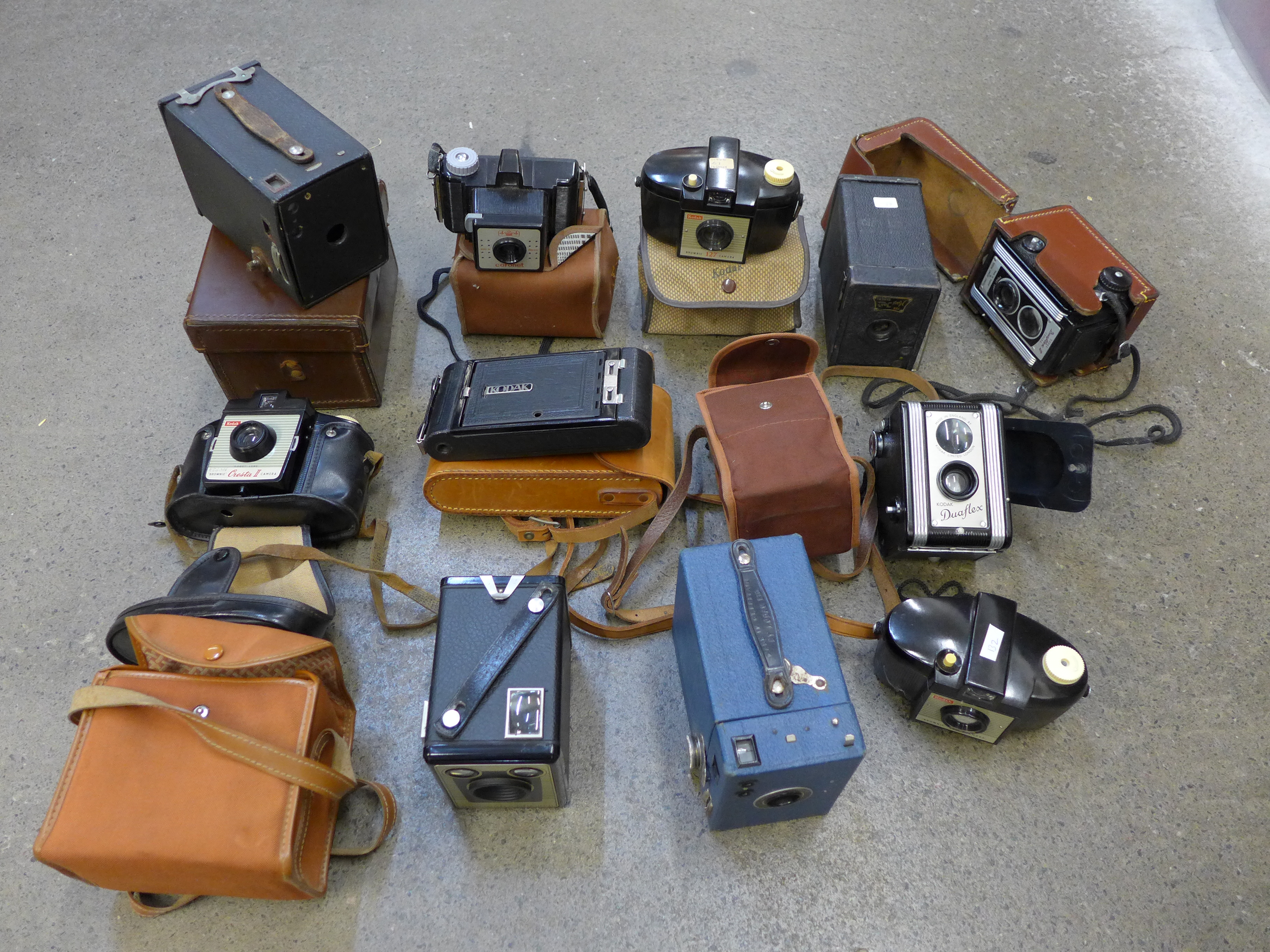 A collection of old cameras, box brownie, folding, Kodak Duaflex II, doll, etc.