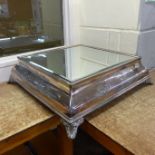 A large square silver plated cake stand with mirror top, 51cm square