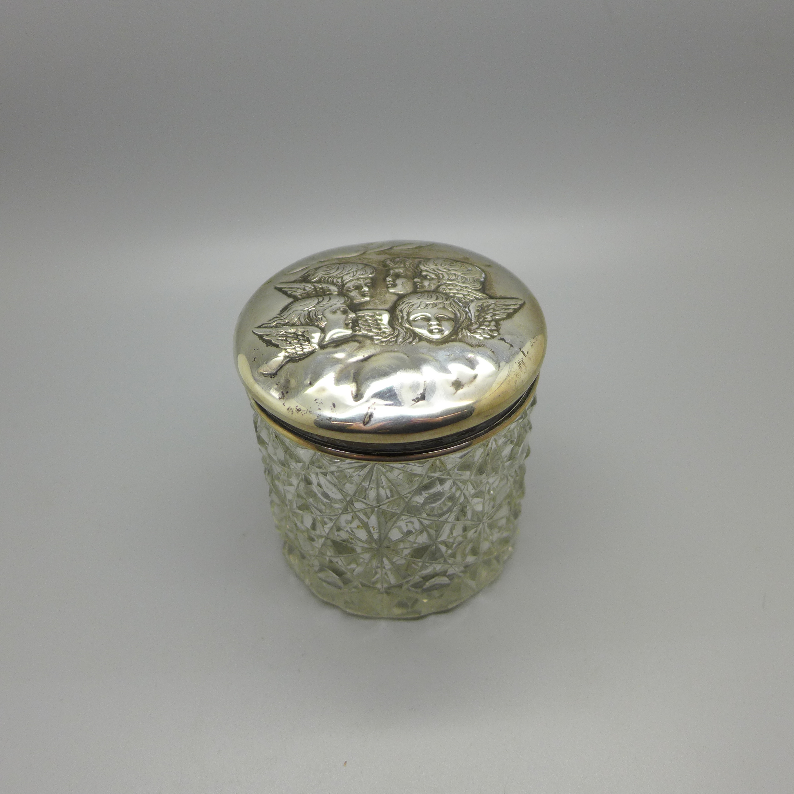 A silver topped cut glass jar decorated with Reynolds angels, Birmingham 1904