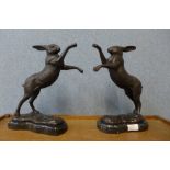 A pair of bronze boxing hares, on black marble socle