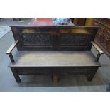 An Arts and Crafts carved oak settle
